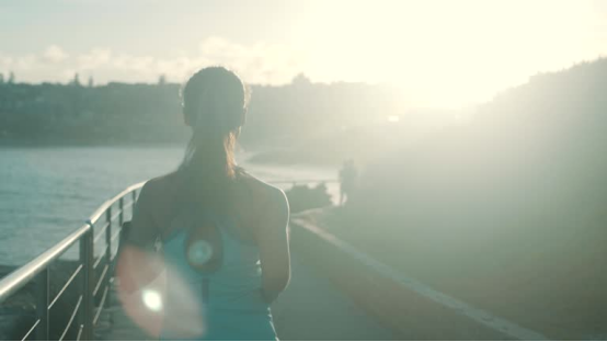 A person jogging along a waterfront path at sunrise, representing the active lifestyle that can benefit from post-workout showers with a shower filter.